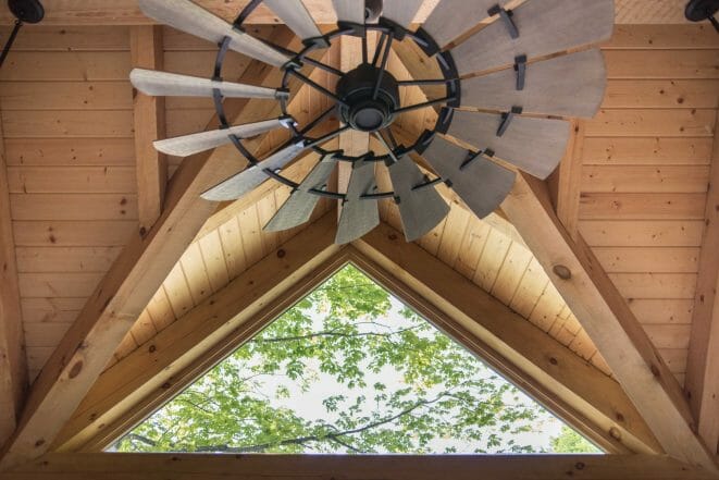 Overhead industrial farm fan with skylight in a timber frame post and beam workout room barn